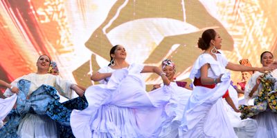 Performers in flowing dresses dance on an outdoor stage at IMMERSE.